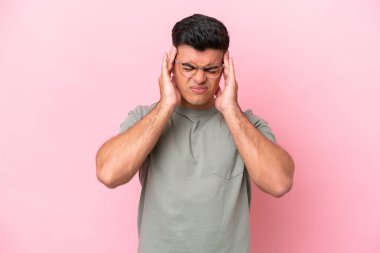 Pembe arka planda yalnız ve başı ağrıyan beyaz, yakışıklı genç bir adam.