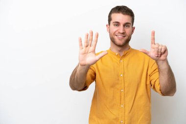 Beyaz arka planda izole edilmiş genç beyaz adam yediyi parmaklarıyla sayıyor