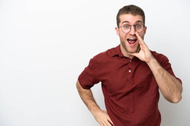 Beyaz arka planda izole edilmiş genç beyaz bir adam ağzı açık bağırıyor.