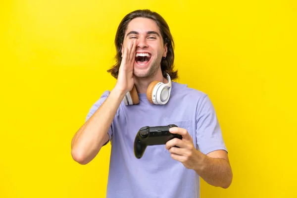 若いですハンサムなCaucasian男遊びますとともにビデオゲームコントローラ上の隔離された上に黄色の背景叫びとともに口を大きく開きます — ストック写真