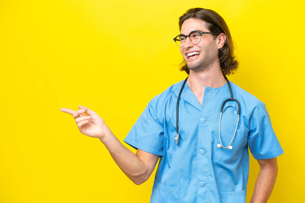 Young surgeon caucasian man isolated on yellow background pointing finger to the side and presenting a product