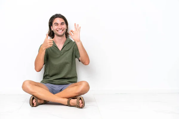 Joven Hombre Guapo Sentado Suelo Aislado Sobre Fondo Blanco Mostrando — Foto de Stock