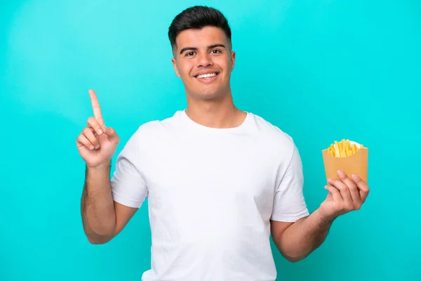 Ung Kaukasier Man Fånga Pommes Frites Isolerad Blå Bakgrund Pekar — Stockfoto