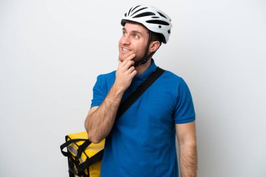 Beyaz arka planda izole edilmiş termal sırt çantalı beyaz bir adam yukarı bakarken bir fikir düşünüyor.