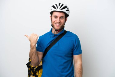 Beyaz arka planda izole edilmiş termal sırt çantalı beyaz bir adam bir ürün sunmak için kenarı işaret ediyor.