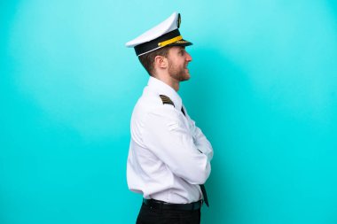 Kafkasyalı uçak pilotu mavi arka planda yan pozisyonda izole edildi.