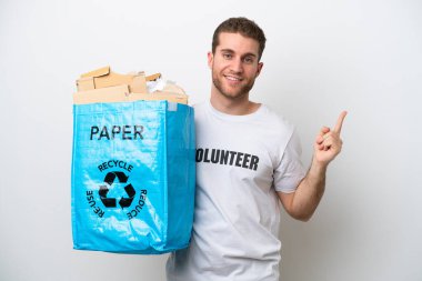 Beyaz arka planda izole edilmiş bir şekilde geri dönüşüm için elinde kağıt dolu bir torba tutan beyaz bir adam en iyinin işareti olarak parmağını kaldırıyor.