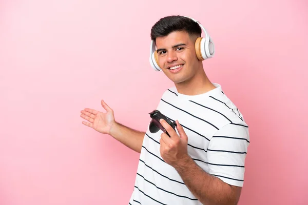 Νεαρός Όμορφος Άνδρας Παίζει Ένα Χειριστήριο Βιντεοπαιχνιδιών Απομονωμένο Ροζ Φόντο — Φωτογραφία Αρχείου