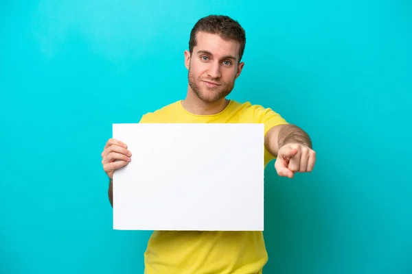 Jovem Caucasiano Isolado Fundo Azul Segurando Cartaz Vazio Apontando Para — Fotografia de Stock