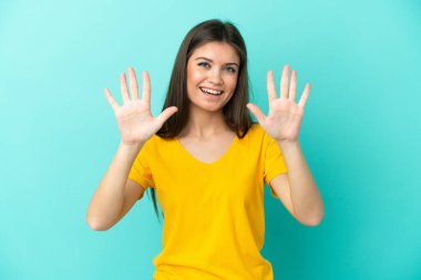 Mavi arka planda izole edilmiş genç beyaz kadın parmaklarıyla ona kadar sayıyor.