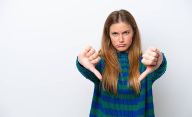 Beyaz arka planda izole edilmiş genç beyaz kadın baş parmağını iki eliyle aşağı gösteriyor.