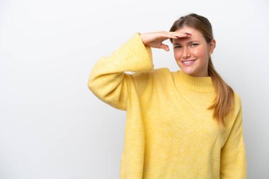 Beyaz arka planda soyutlanmış genç beyaz bir kadın, bir şeye bakmak için uzaklara bakıyor.