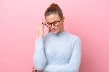 Pembe arka planda izole edilmiş, başı ağrıyan beyaz bir kadın.