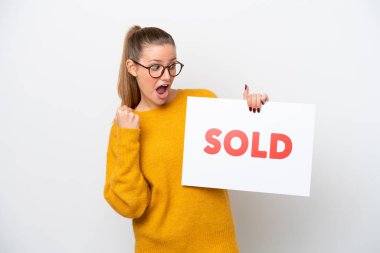 Beyaz arka planda izole edilmiş genç beyaz bir kadın. Elinde satılmış bir afiş var ve zaferi kutluyor.