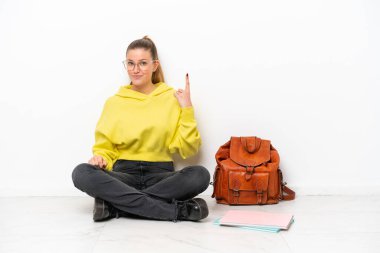 Beyaz arka planda beyaz bir zeminde oturan genç beyaz kadın işaret parmağıyla işaret etmek harika bir fikir.