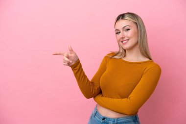 Pembe arka planda izole edilmiş genç beyaz bir kadın.