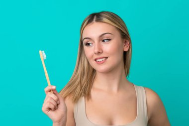 Mavi arka planda diş fırçasıyla izole edilmiş beyaz bir kadın.