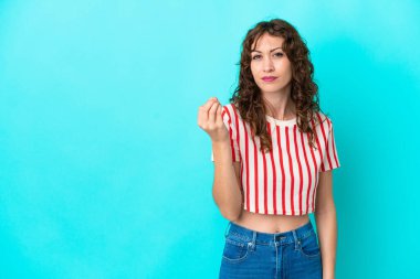 Mavi arka planda izole edilmiş kıvırcık saçlı genç bir kadın İtalyan jesti yapıyor.