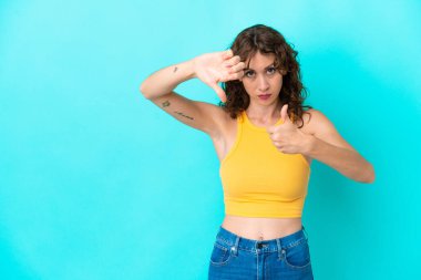 Mavi arka planda, kıvırcık saçlı genç bir kadın, iyiye-kötüye işaret yapıyor. Evet ya da hayır arasında kararsız