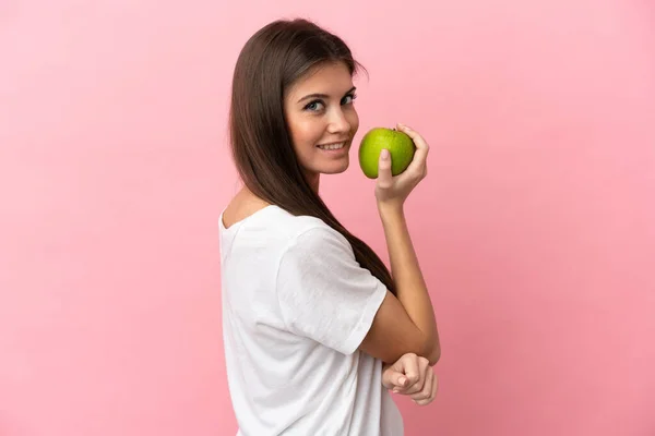 ピンクの背景に孤立した若い白人女性がリンゴを食べる — ストック写真
