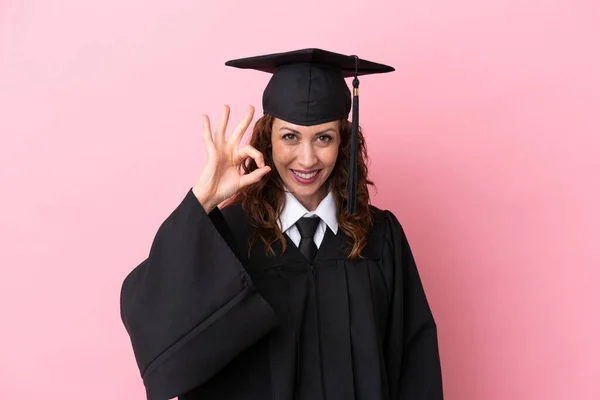 Young university graduate woman isolated on pink background showing ok sign with fingers