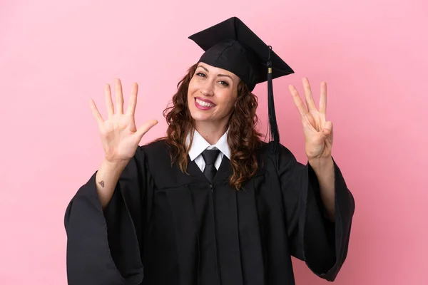 Young university graduate woman isolated on pink background counting eight with fingers