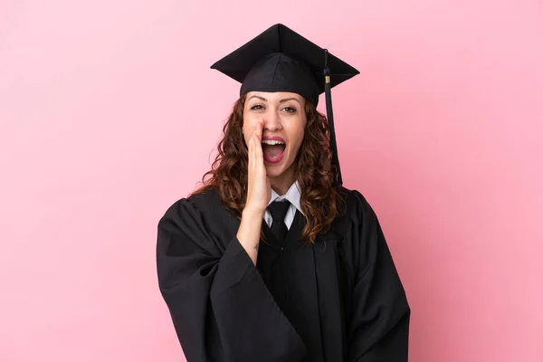 Young university graduate woman isolated on pink background shouting with mouth wide open