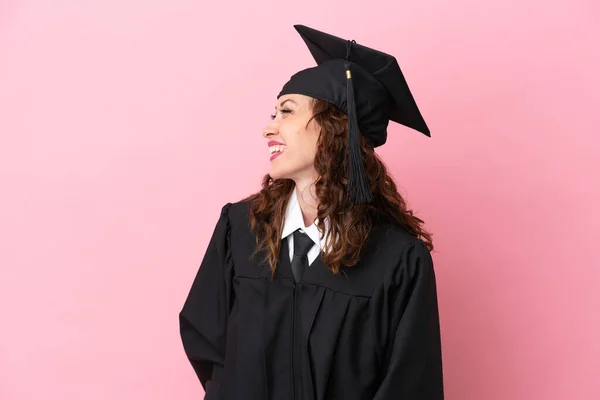 Young university graduate woman isolated on pink background laughing in lateral position