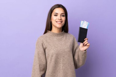 Genç beyaz kadın, mor arka planda izole edilmiş. Pasaport ve uçak biletleriyle tatilde mutlu.