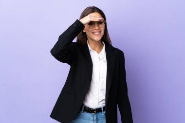 Mor arka planda izole edilmiş bir iş kadını, bir şeye bakmak için çok uzaklara bakıyor.