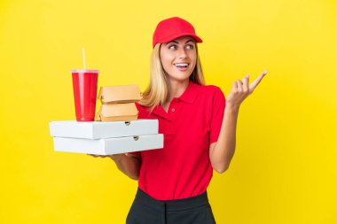 Delivery Uruguayan woman holding fast food isolated on yellow background intending to realizes the solution while lifting a finger up