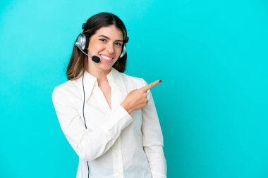 Tele pazarlamacı İtalyan kadın mavi arka planda izole edilmiş bir kulaklıkla çalışıyor.