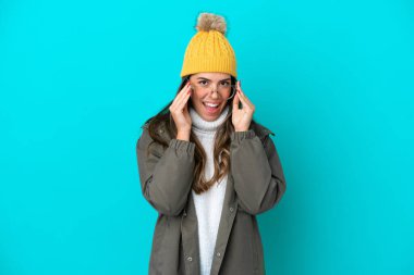 Mavi arka planda gözlüklü, kışlık ceket ve şapka giyen genç İtalyan kadın şaşırdı.