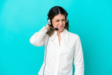 Tele pazarlamacı İtalyan kadın kulaklıkla çalışıyor. Mavi arka planda, boynu ağrıyan bir kadın.