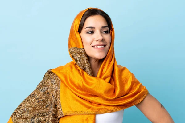 若いですモロッコの女性で伝統的な衣装は 腰と笑顔で腕でポーズ青の背景に隔離 — ストック写真