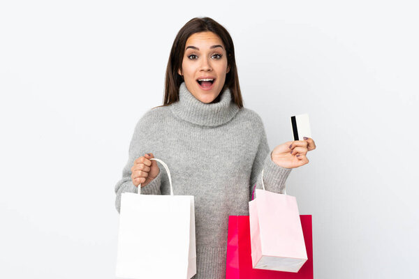 Молодая кавказка изолирована на белом фоне, держит сумки с покупками и удивлена