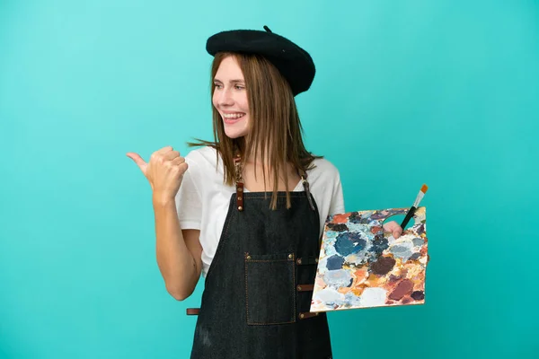 Młoda Artystka Angielska Kobieta Trzyma Paletę Odizolowanych Niebieskim Tle Wskazując — Zdjęcie stockowe