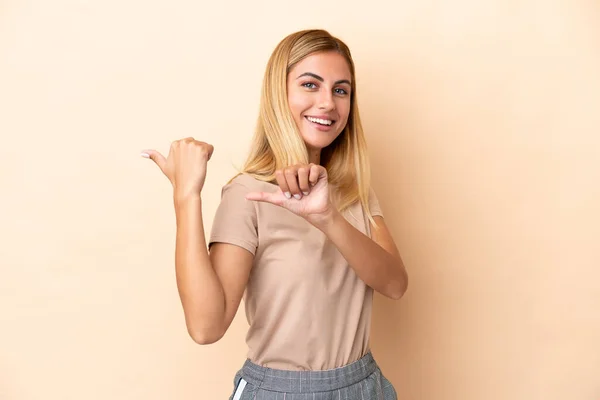 Menina Uruguaia Loira Isolada Fundo Bege Apontando Para Lado Para — Fotografia de Stock