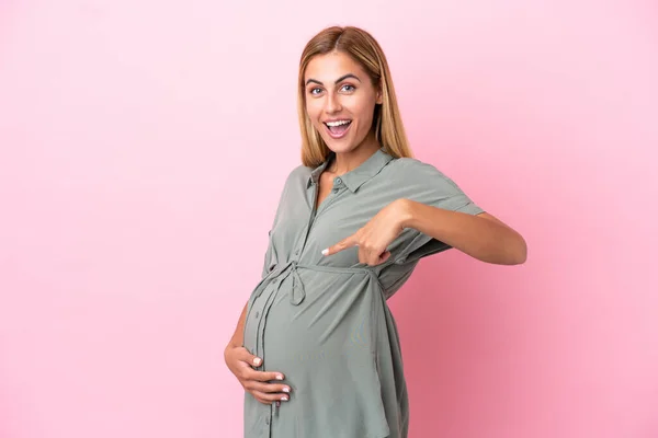 若いウルグアイの女性は妊娠中の青い背景に隔離され 腹を指しています — ストック写真