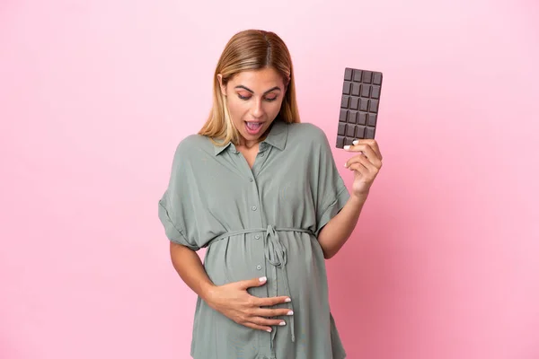 Mladá Uruguayská Žena Izolované Modrém Pozadí Těhotná Drží Čokoládu Překvapeným — Stock fotografie