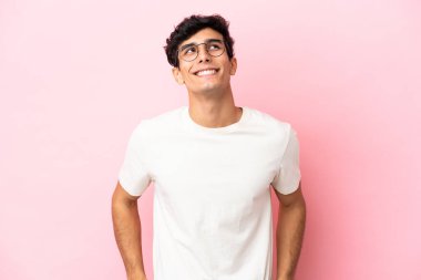 Arjantinli genç bir adam pembe arka planda izole edilmiş.