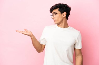 Pembe arka planda izole edilmiş genç Arjantinli adam kopyalama alanını şüpheyle tutuyor