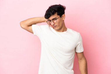 Arjantinli genç bir adam pembe arka planda izole edilmiş, boyun ağrısı var.