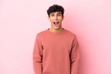 Arjantinli genç bir adam pembe arka planda izole edilmiş ve yüzünde sürpriz bir ifade var.