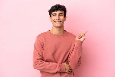 Pembe arka planda izole edilmiş genç Arjantinli adam mutlu ve dik duruyor.