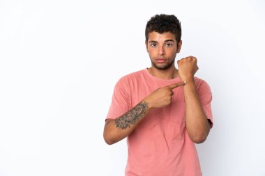Genç, yakışıklı Brezilyalı bir adam beyaz arka planda izole edilmiş, geç kalma jesti yapıyor.