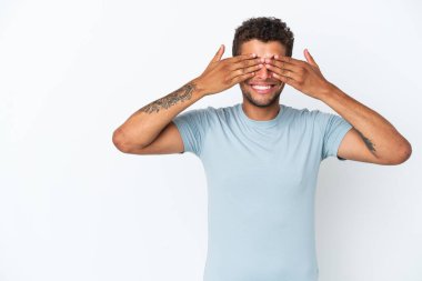 Genç ve yakışıklı Brezilyalı bir adam beyaz arka planda izole edilmiş, gözleri kapalı ve gülümsüyor.