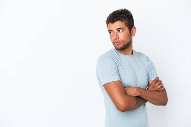Beyaz arka planda izole edilmiş yakışıklı Brezilyalı adam kollarını kavuşturuyor.