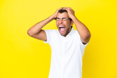 Sarı arka planda izole edilmiş yakışıklı Brezilyalı bir adam stresli.