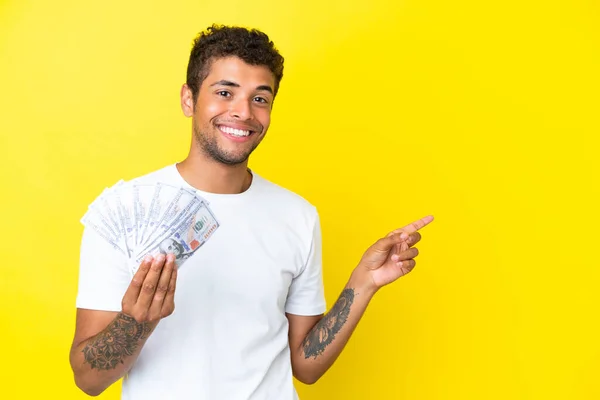 Νεαρός Βραζιλιάνος Που Παίρνει Πολλά Χρήματα Απομονωμένος Κίτρινο Φόντο Δείχνοντας — Φωτογραφία Αρχείου